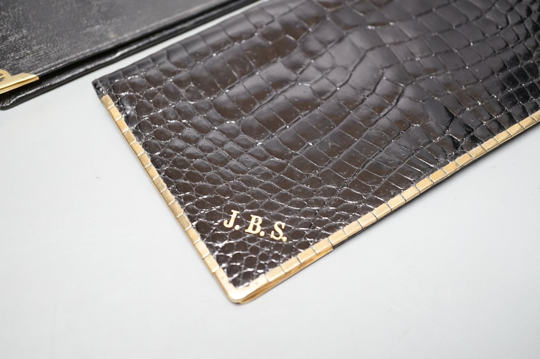 An Alfred Dunhill gold plate mounted leather wallet, 18.9cm, and one other 9ct gold mounted leather wallet initialled J.B.S., 17.9cm.